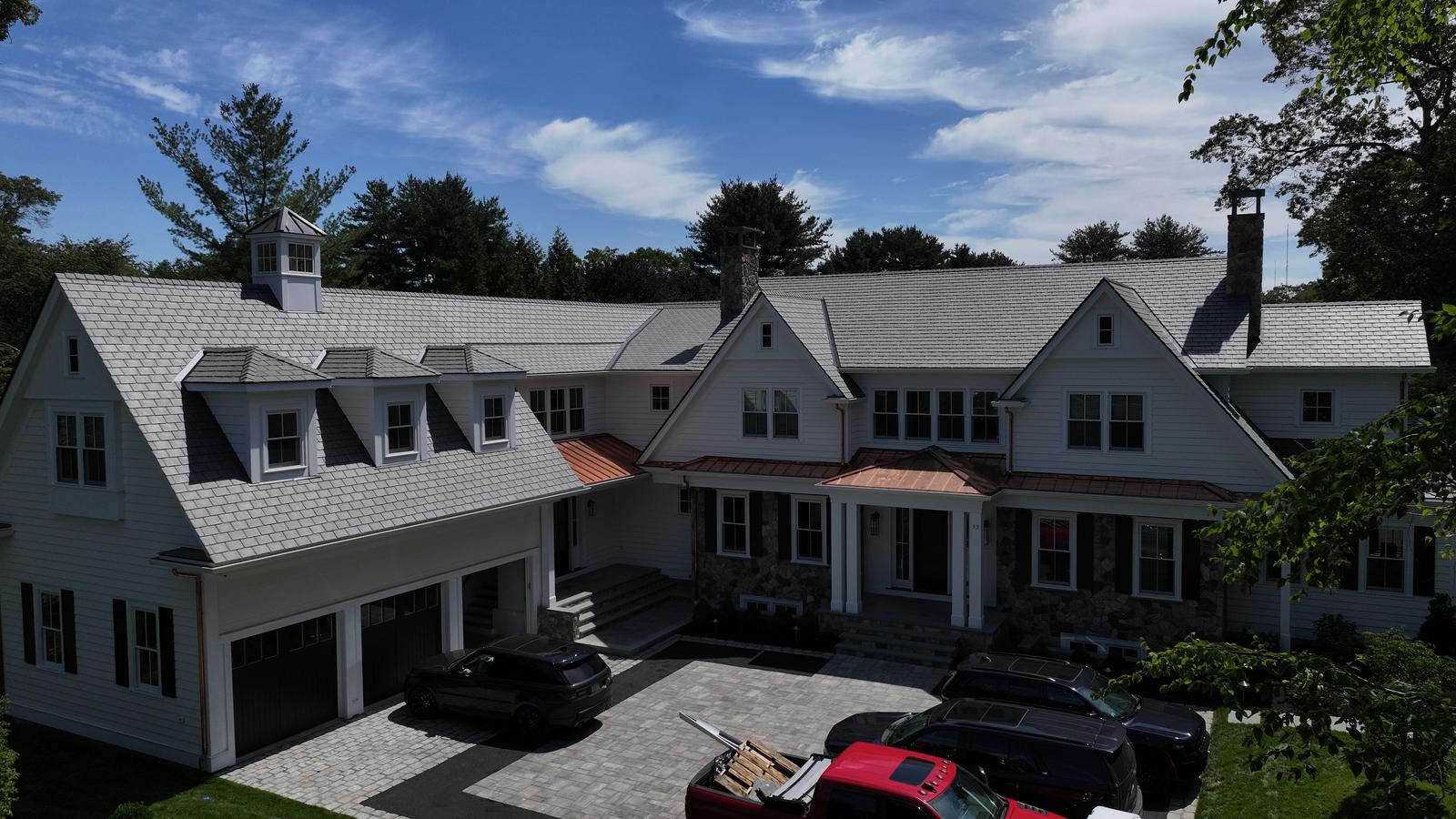 Shingle-style home with dormers and a cupola under a gray shingle roof
