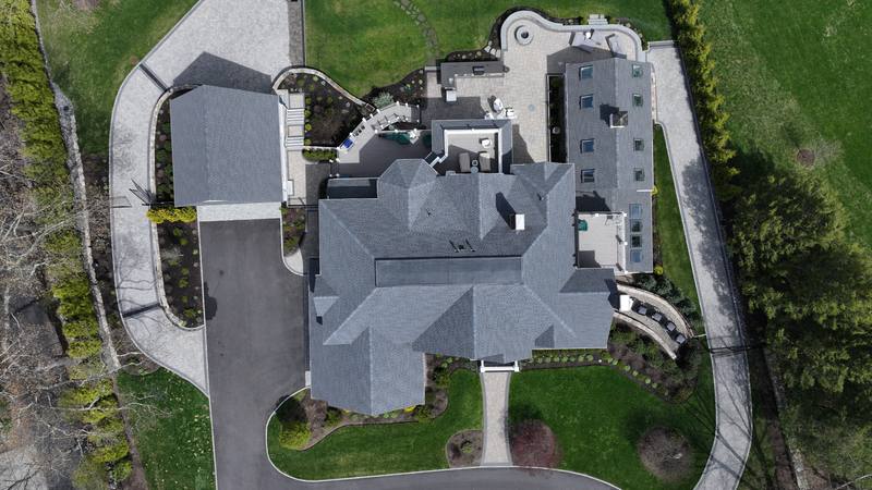 Hip roof on a large home with a curved driveway, top-down aerial