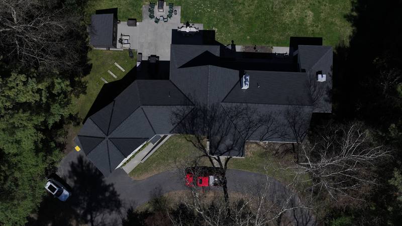 Black shingle roof on a wooded lot, top-down aerial