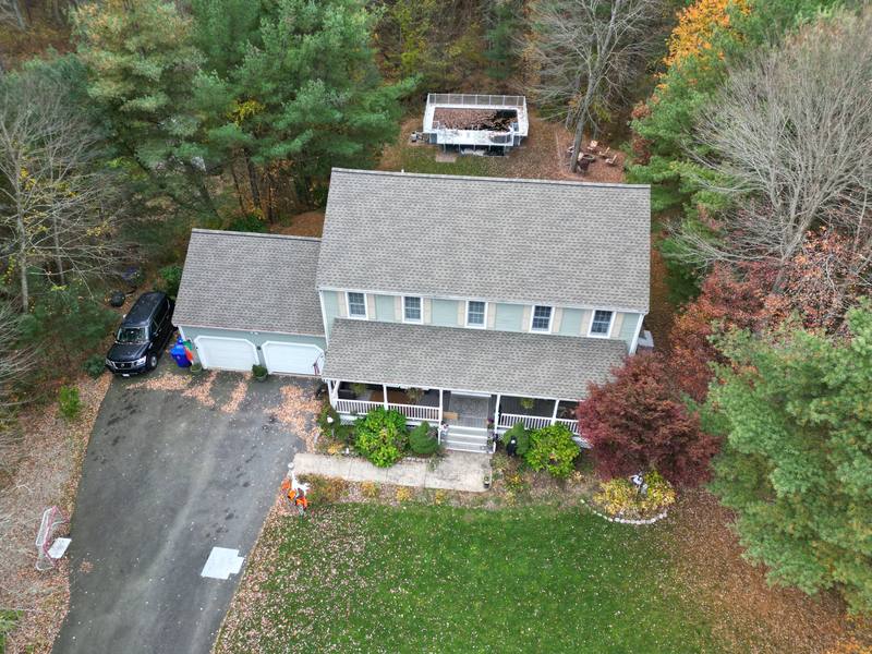 Colonial with a gray shingle roof and farmer's porch in the fall