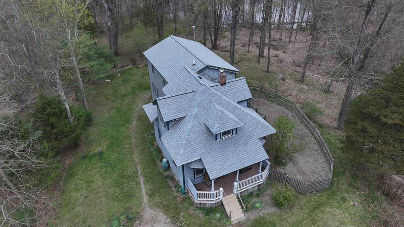Tall home with a gray shingle roof in the woods