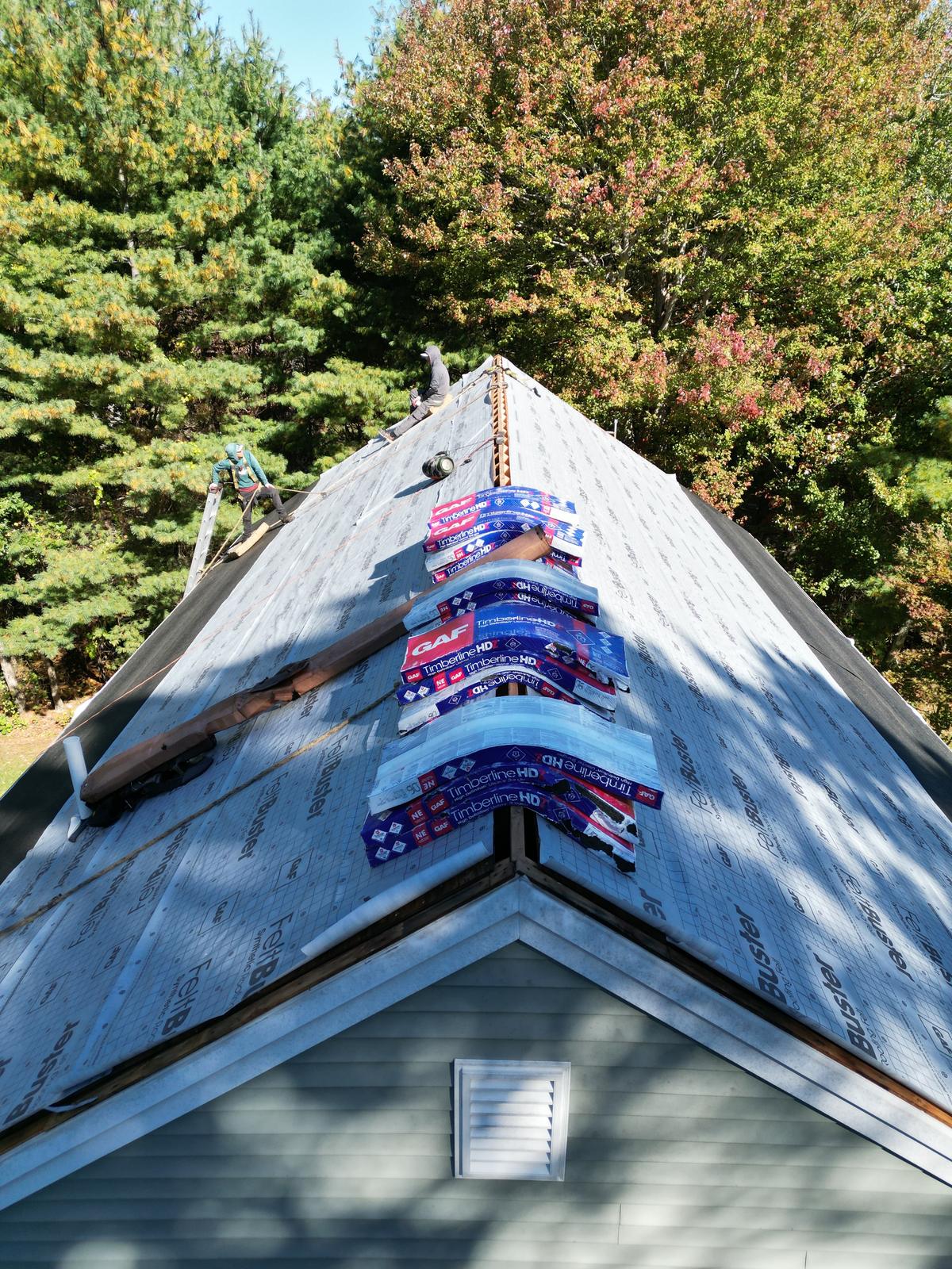 GAF shingle bundles staged on the ridge of a roof being replaced